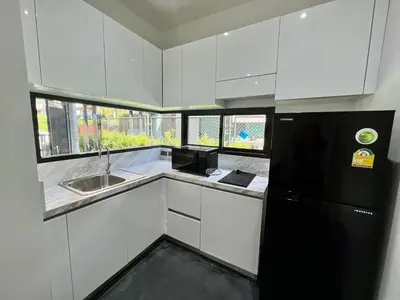 a kitchen with white cabinets and a black refrigerator at 2 BR Modern Pool Villa Chalong in Ban Suan