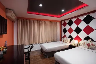 a hotel room with two beds and a desk and a table at Chilli Salza Patong in Patong Beach