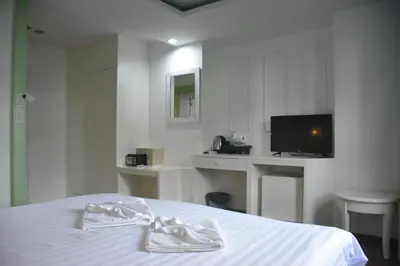 a white bedroom with a bed and a television at Chilli Salza Patong in Patong Beach