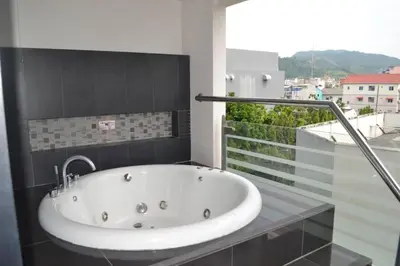 a white bath tub in a bathroom with a window at Absolute Bangla Suites 69sqm with Jacuzzi in Patong Beach