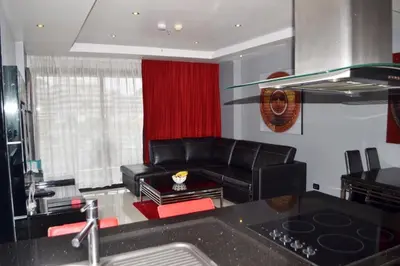 a living room with a black leather couch and red curtains at Absolute Bangla Suites 69sqm with Jacuzzi in Patong Beach