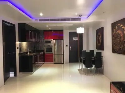 a kitchen with red cabinets and black appliances and black chairs at Absolute bangla suites 65 sqm with Jacuzzi in Patong Beach