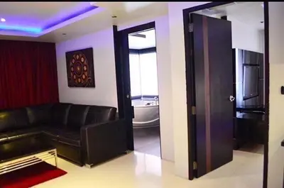 a living room with a black leather couch and a bathroom at Absolute bangla suites 65 sqm with Jacuzzi in Patong Beach