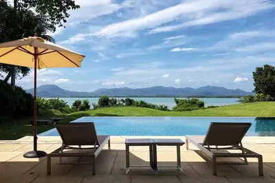 two chairs and a table with an umbrella next to a pool at \u9759\u6e7e\u4e4b\u8679VILLA SHOOWA Cape Yamu\u5962\u534e\u6d77\u666f\u522b\u5885 in Ban Bang La