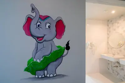a bathroom with a painting of an elephant on the wall at Friends Hostel - Phuket Airport in Nai Yang Beach