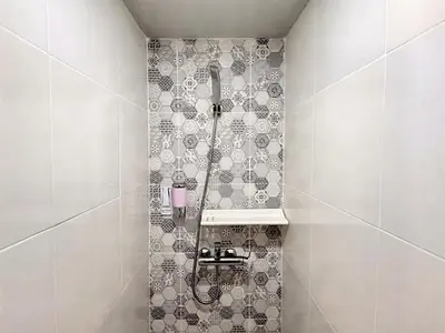 a bathroom with a shower with a tile wall at Friends Hostel - Phuket Airport in Nai Yang Beach