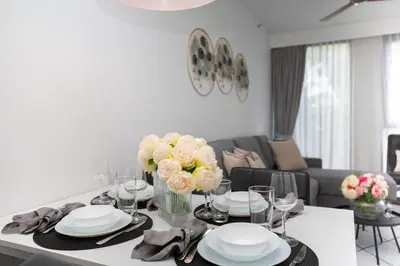 a dining room table with plates and flowers on it at Cassia 1BR City View apt by NLA in Bang Tao Beach