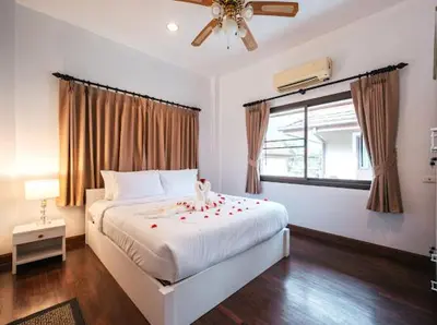 a bedroom with a large white bed with red flowers on it at Pool Villa Tambon Patong in Patong Beach
