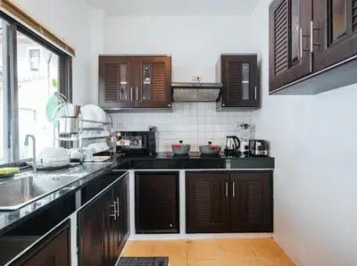 a kitchen with brown cabinets and a sink and a window at Pool Villa Tambon Patong in Patong Beach