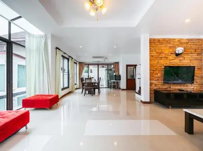 a living room with a red couch and a brick wall at Pool Villa Tambon Patong in Patong Beach