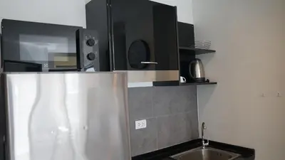a kitchen with a sink and a microwave at Island Escape 1BR T1-206 in Chalong