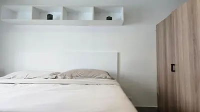 a bedroom with a bed with white walls and shelves at Island Escape 1BR T1-206 in Chalong