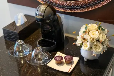 a table with a coffee maker and cupcakes and a vase of flowers at Studio Apartment in Bangla Rd in Patong Beach