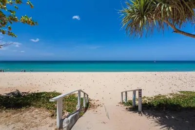 a sandy beach with a staircase in the sand at Near beach hostel in Bang Tao Beach
