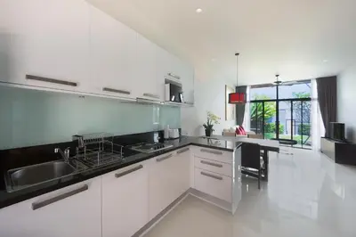 a kitchen with white cabinets and black counter tops at Saiyuan Estate by TropicLook in Rawai Beach