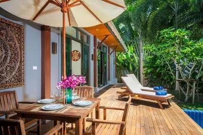 a wooden deck with a table and chairs and an umbrella at Saiyuan Estate by TropicLook in Rawai Beach
