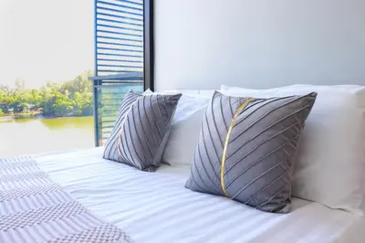 a bed with two pillows on it with a window at Cassia 3BR Sea View apt by NLA in Bang Tao Beach