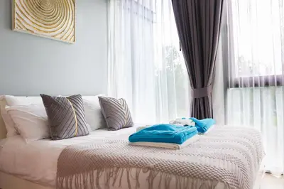 a bed with a teddy bear sitting on it in front of a window at Cassia 3BR Sea View apt by NLA in Bang Tao Beach