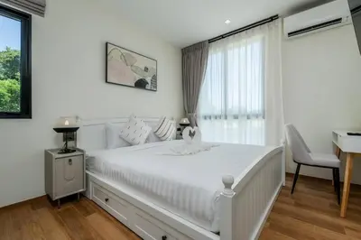 a white bedroom with a large white bed and a desk at Two Flamingo Apartment 1 in Nai Yang Beach