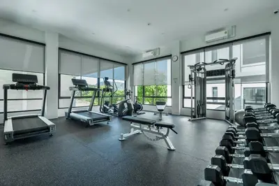 a gym with chairs and machines in a room with windows at Two Flamingo Apartment 1 in Nai Yang Beach