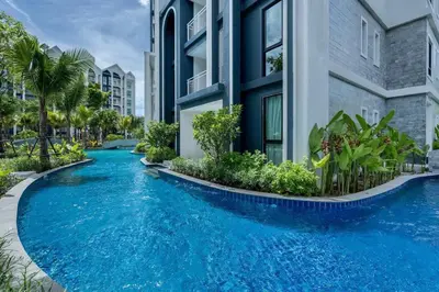a swimming pool in front of a building with blue water at Two Flamingo Apartment 1 in Nai Yang Beach