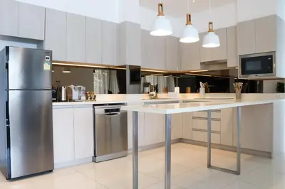 a kitchen with a white counter and a refrigerator at Cassia 3BR with Terrace Sea view apt by NLA in Phuket Town