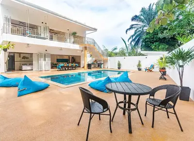 a patio with a table and chairs and a pool at Amidst tropical plantations and striking mountain views in Ban Khlong Haeng