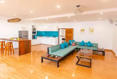 a living room with a green couch and a kitchen at Amidst tropical plantations and striking mountain views in Ban Khlong Haeng