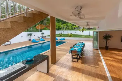 a pool in a house with a dining room with a table at Amidst tropical plantations and striking mountain views in Ban Khlong Haeng