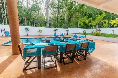 a blue table with chairs and a pool in the background at Amidst tropical plantations and striking mountain views in Ban Khlong Haeng