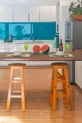 a kitchen with two wooden stools and a counter top at Amidst tropical plantations and striking mountain views in Ban Khlong Haeng