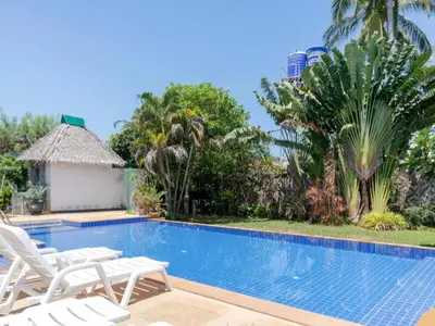 a swimming pool with white chairs and palm trees at OYO 1046 Noppharat resort in Ao Nang Beach