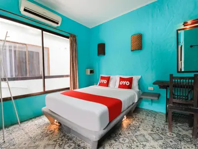 a bedroom with blue walls and a bed with red pillows at OYO 1103 Pirates House Hotel in Phi Phi Don