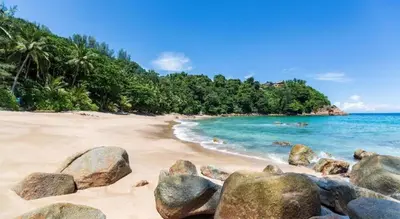 a beach with rocks in the sand and the ocean at Long Beach Hotel Patong in Patong Beach