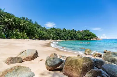 a beach with rocks in the sand and the ocean at OYO 232 Patong City Hometel in Patong Beach