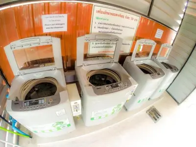 four washing machines are lined up in a laundry room at My Place Phuket Airport Mansion in Ban Bo Han