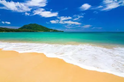 a beach with the ocean and a hill in the background at My Place Phuket Airport Mansion in Ban Bo Han
