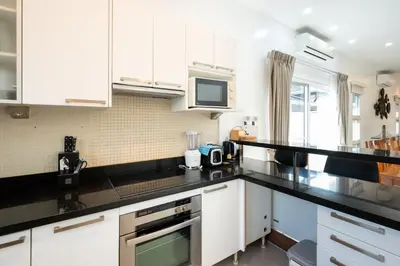 a kitchen with white cabinets and black counter tops at Tranquil 3 Bedroom Garden Pool Villa in Laguna Phuket