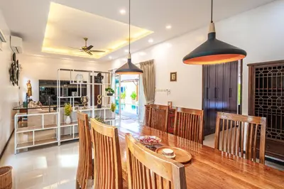 a dining room with a wooden table and chairs at Tranquil 3 Bedroom Garden Pool Villa in Laguna Phuket