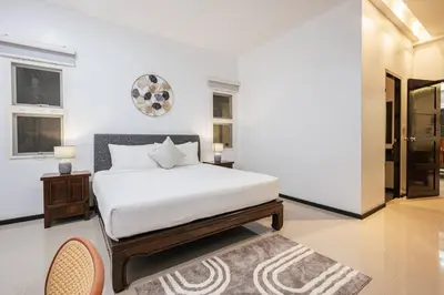 a white bedroom with a bed and a rug at Tranquil 3 Bedroom Garden Pool Villa in Laguna Phuket