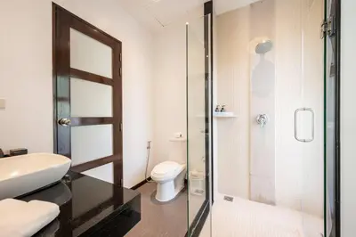 a bathroom with a toilet and a glass shower at Tranquil 3 Bedroom Garden Pool Villa in Laguna Phuket