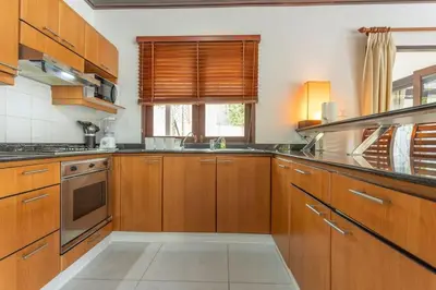 a large kitchen with wooden cabinets and a window at Surin 4-Bed Luxury Retreat with Private Pool V131 in Thalang