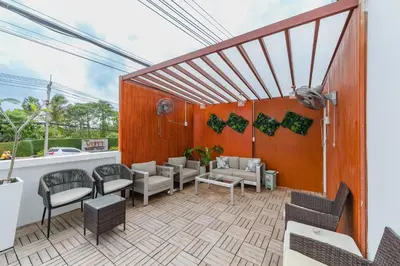 a patio with couches and chairs on a wooden wall at De Blue Sea Rawai Hotel in Ban Saiyuan (1)
