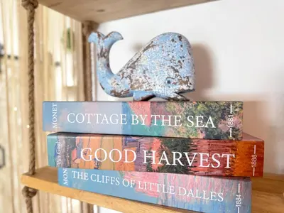 a stack of books sitting on top of a shelf at Sea Dreamer Ao Yon Beach House in Ban Ao Makham