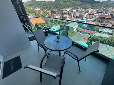 a table and chairs on a balcony with a view at Emerald Terrace Condo 9-1 Bed City & Mountain in Patong Beach