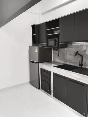 a kitchen with black cabinets and a sink at Suthida Resort in Rawai Beach