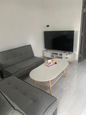 a living room with a couch and a table and a tv at Suthida Resort in Rawai Beach