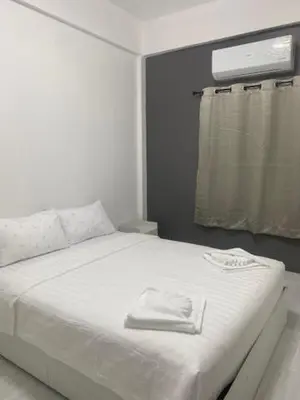 a white bed in a room with a window at Suthida Resort in Rawai Beach