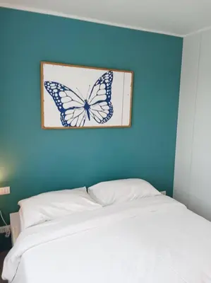 a butterfly picture on a blue wall above a bed at 2BR Aparment Near The Beach T2-717 in Phuket Town