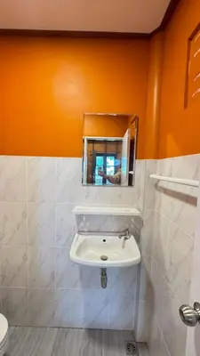 a bathroom with a white sink and an orange wall at Cheriya bungalow Kohyaonoi in Ban Laem Sai